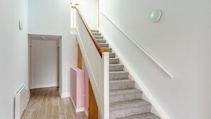 Een trap met een houten leuning en beklede treden die naar een verdieping leiden.