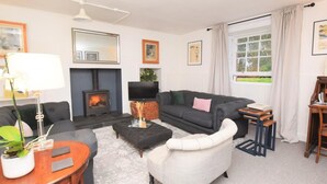 A living room with a fireplace, sofa, armchair, and a television. - 2 Bed in Beauly (oc-78962) (Windhill)