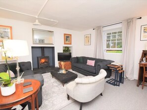 Ein Wohnzimmer mit Kamin, Sofa, Sesseln und Fernseher.