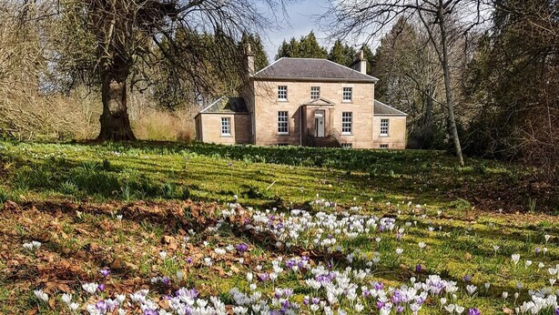 A stone building with a symmetrical facade, a central entrance, and a well-maintained lawn with blooming crocuses. - 2 Bed in Beauly (oc-78962) (Windhill)