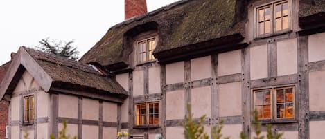 A traditional half-timbered house with a thatched roof and a chimney.
