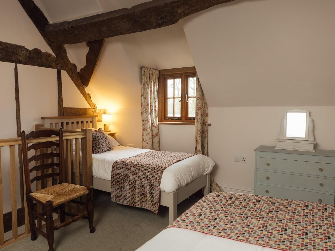 Une chambre à coucher avec un lit, une chaise, une commode et une fenêtre.