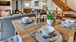Ein gemütlicher Essbereich mit einem Holztisch, gedeckt für zwei Personen, einem Kamin und einer Treppe.
