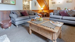 Ein gemütliches Wohnzimmer mit zwei grauen Sofas, einem Holztisch und einer Steinwand.