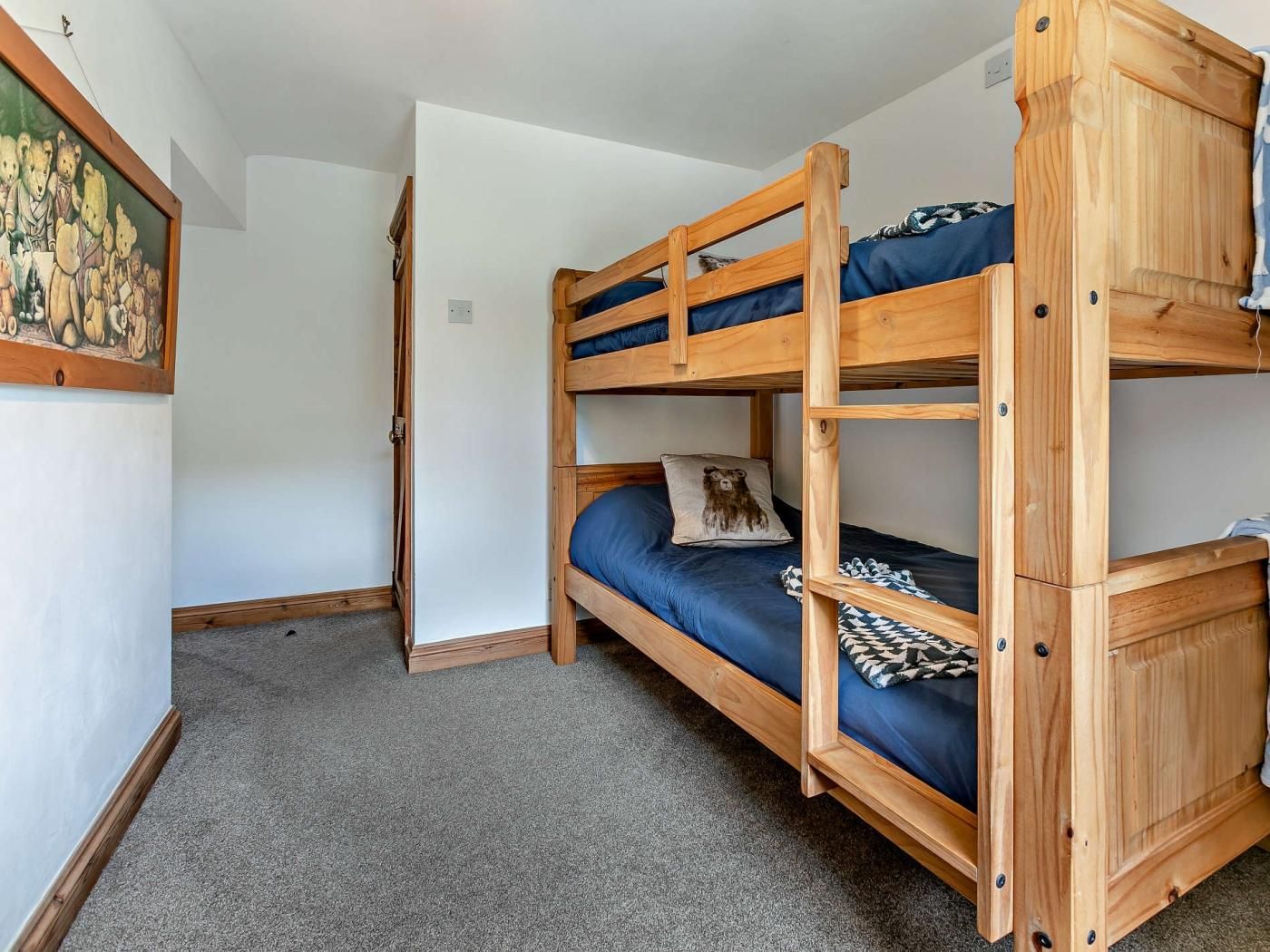 A bunk bed room with a wooden frame, a door, and a painting on the wall.