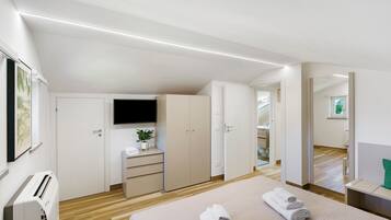 Une chambre moderne avec un lit, une télévision, une armoire et un bureau agrémenté d’une plante.