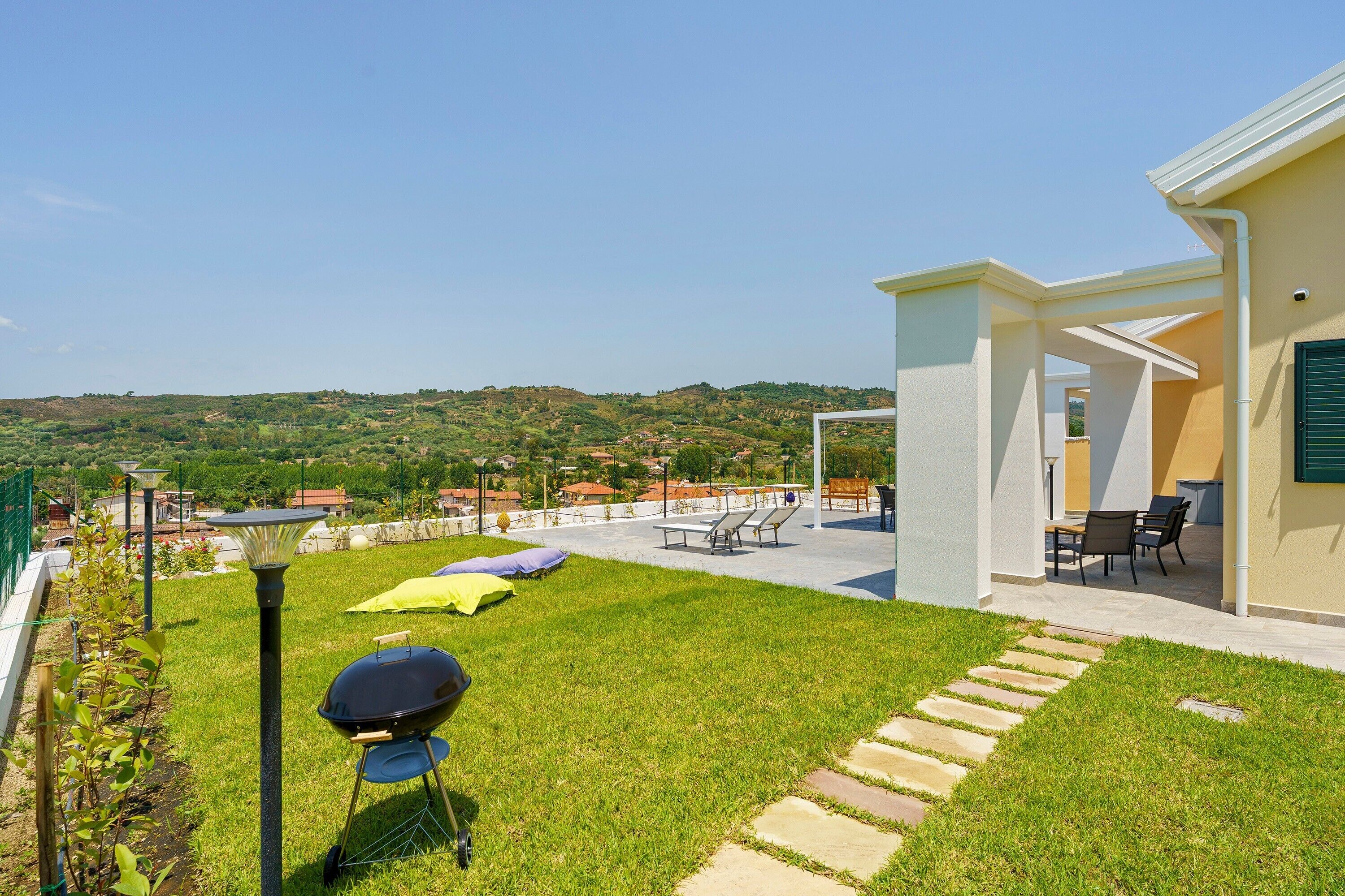 A patio with outdoor furniture, a barbecue grill, and a view of the surrounding landscape.