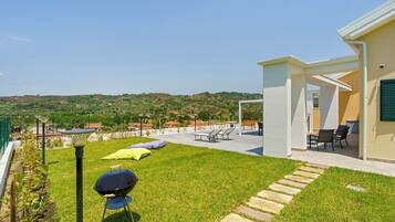 A patio with outdoor furniture, a barbecue grill, and a view of the surrounding landscape.