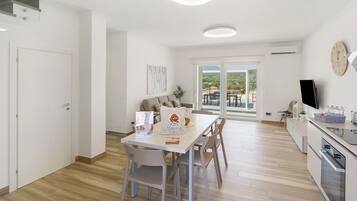 A modern kitchen with a dining area, a large window, and a flat-screen TV.