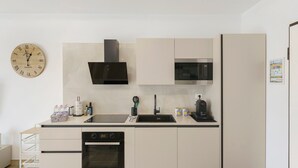 A modern kitchen with a dishwasher, oven, microwave, and a clock on the wall.