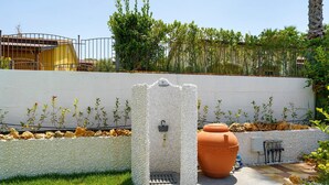A stone structure with a lock, a large terracotta pot, and a paved area with plants.