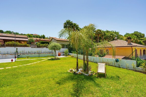 A residential area with a well-maintained lawn, a small tree, and a building with a tiled roof.