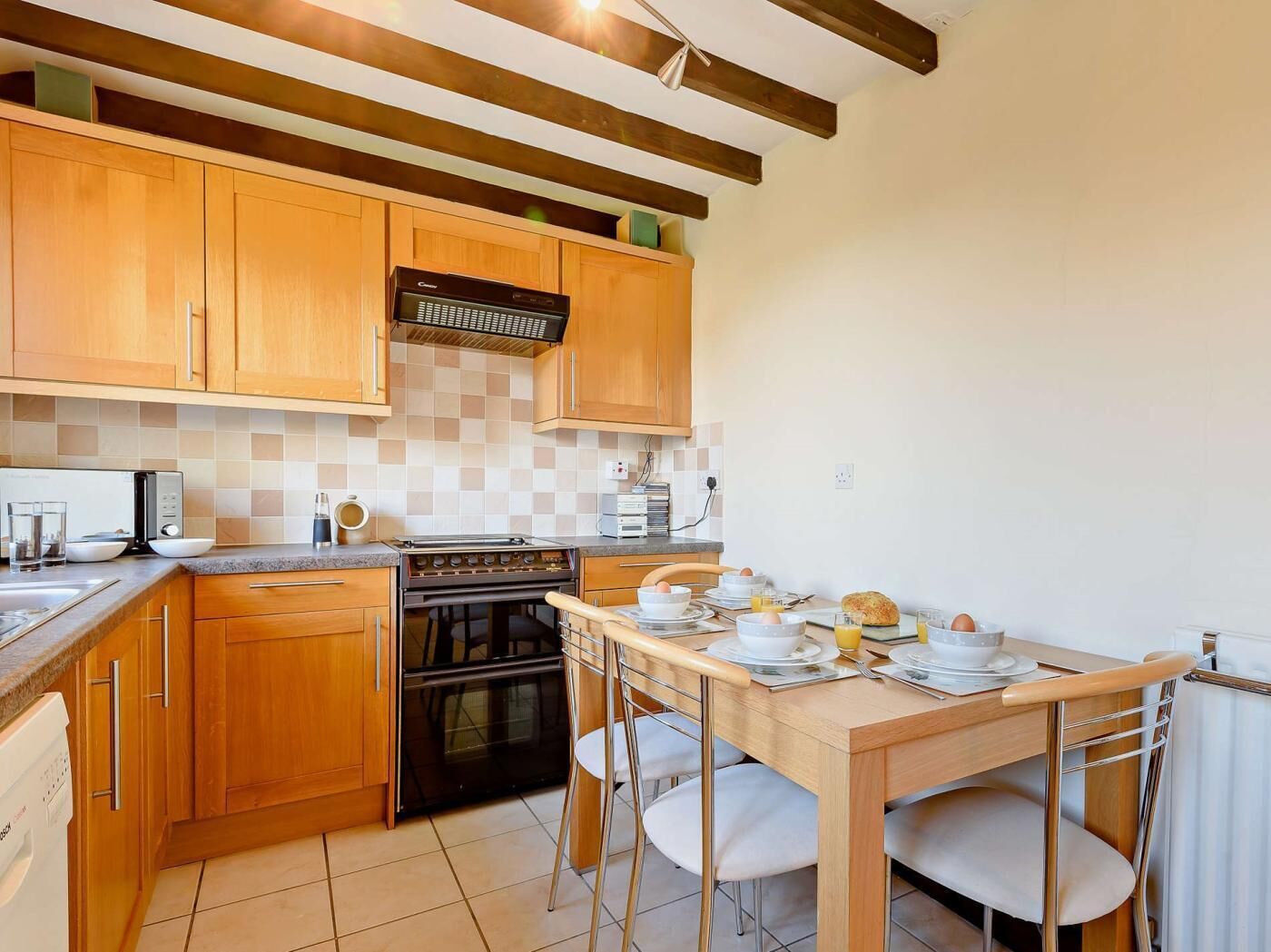 A kitchen with wooden cabinets, a stove, and a dining table set for breakfast.