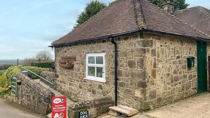 A stone building with a sign for 'CRICKET STAND' and a 'DOG JUICE' sign. - 2 Bed in Matlock (oc-81116) (Crich)