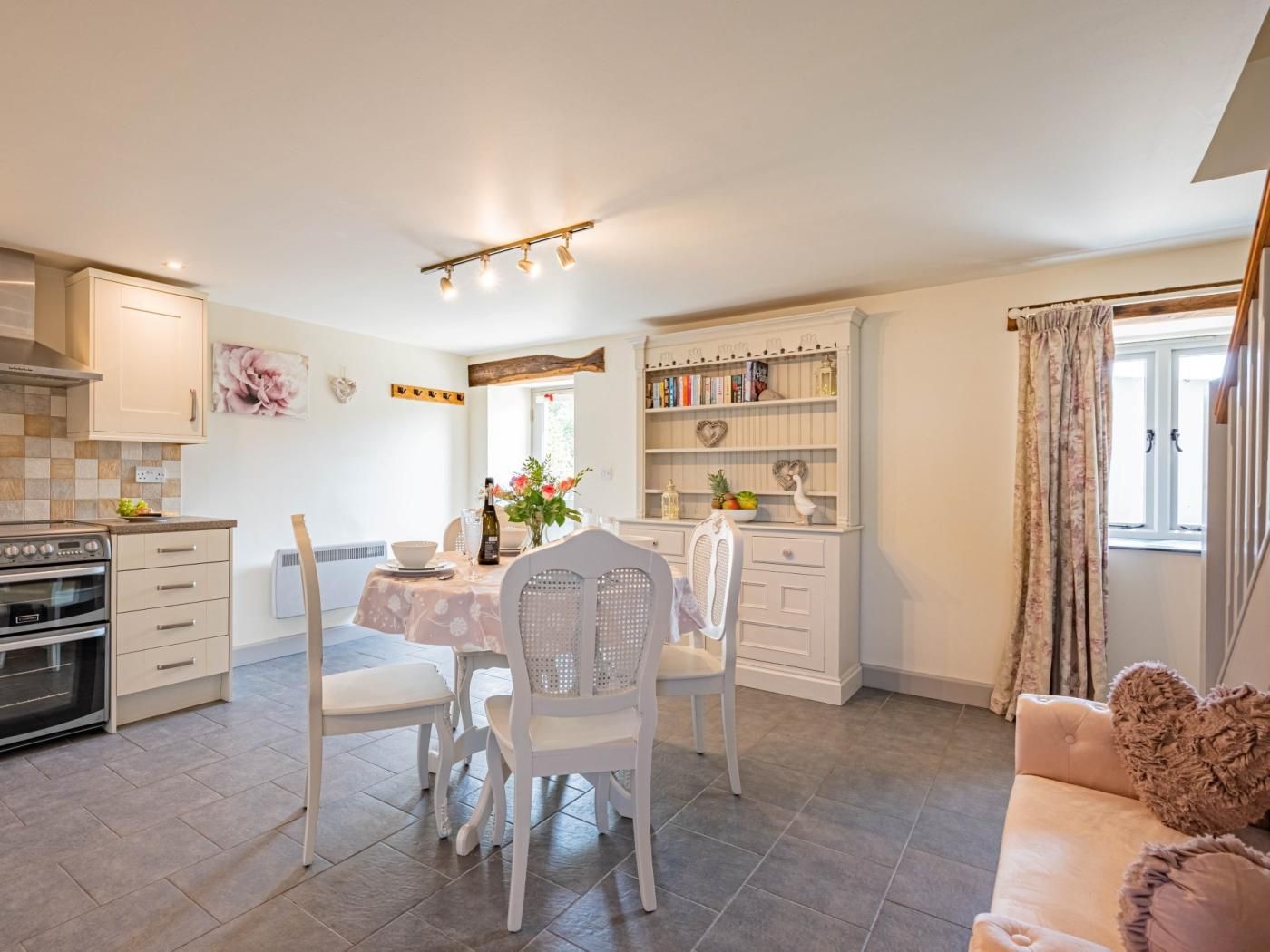 Eine moderne Küche mit weißen Schränken, ein Essbereich mit Tisch für vier Personen und eine gemütliche Wohnarea mit einer Couch.