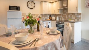 Eine moderne Küche mit weißen Schränken, einer Mikrowelle, einem Backofen und einer Wanduhr.