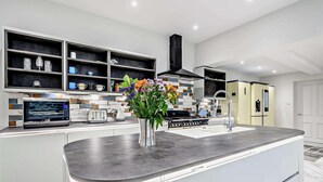 Una cocina moderna con una isla central, estanterías empotradas y diversos electrodomésticos.