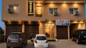 A building with a sign reading 'Shree Madhav Dhama' and another sign with text in a different language. There are two cars parked in front. - Madhav Dham Vrindavan (Vrindavan)