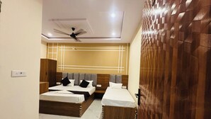 A hotel room with two beds, a ceiling fan, and a modern wall design. - Madhav Dham Vrindavan (Vrindavan)