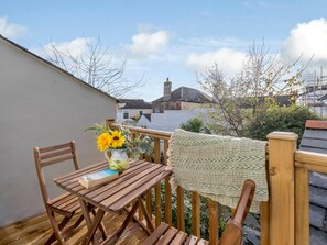 A wooden deck with a table and chairs, a book, and a vase with flowers. - 2 Bed in Bideford (oc-80567) (Appledore)