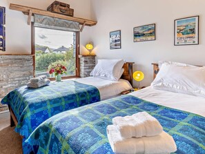 A hotel room with two beds, a stone wall, a window with a view, and framed pictures on the wall. - 2 Bed in Brecon (oc-80519) (Llangorse)