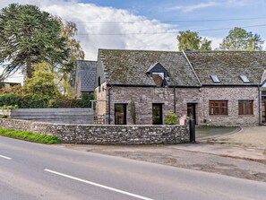 A stone building with a sloped roof, a small porch, and a stone wall in front.