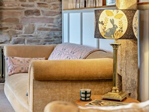 Ein Wohnzimmer mit einer Couch, einer Lampe, einer Tasse und einem Buch auf einem Beistelltisch.