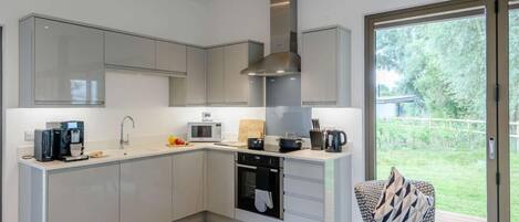 A modern kitchen with grey cabinets, a built-in oven, a microwave, and a coffee maker.