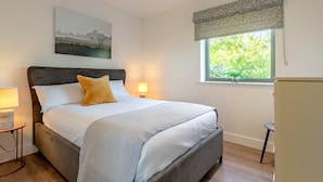 Una camera da letto con un letto, abat-jour, una finestra vista e un quadro appeso al muro.