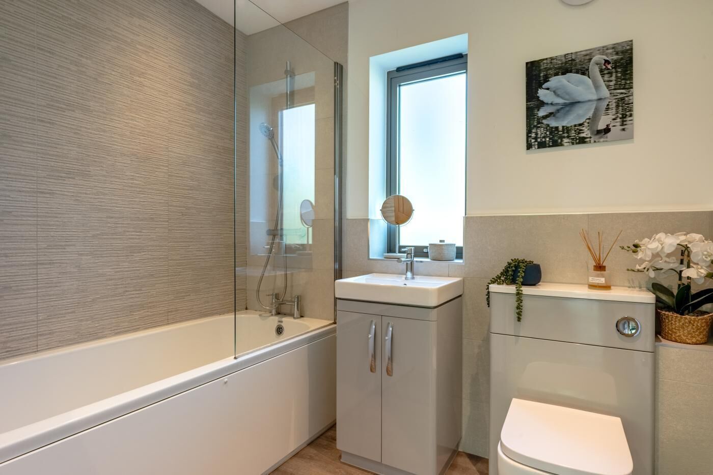 Une salle de bain moderne avec une douche à parois de verre, un lavabo avec un miroir, des toilettes et des plantes décoratives.
