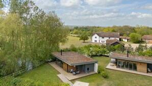 Una casa moderna con un'ampia terrazza, un garage separato e un generoso giardino sul retro.