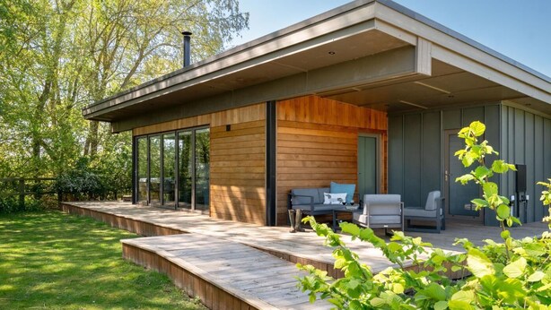Una casa moderna con patio coperto, ampie finestre e un pontile in legno.