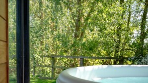 Una vasca idromassaggio con vista su un rigoglioso giardino verde e un recinto in legno.