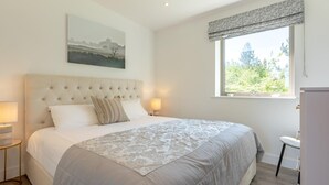 Un dormitorio con una cama grande, una ventana con vistas, una mesita de noche y una lámpara.