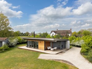 Een modern huis met een plat dak, grote ramen en een bestraat terras.