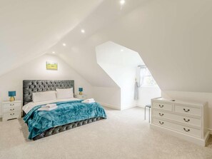 Ein Schlafzimmer mit einem geblatteten Kopfteil, einem weißen Schminktisch und einem Dachfenster.