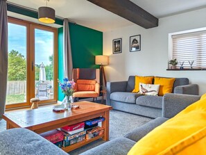 Sala de estar con sofá, sillón, mesa de centro y vista a través de un ventanal.