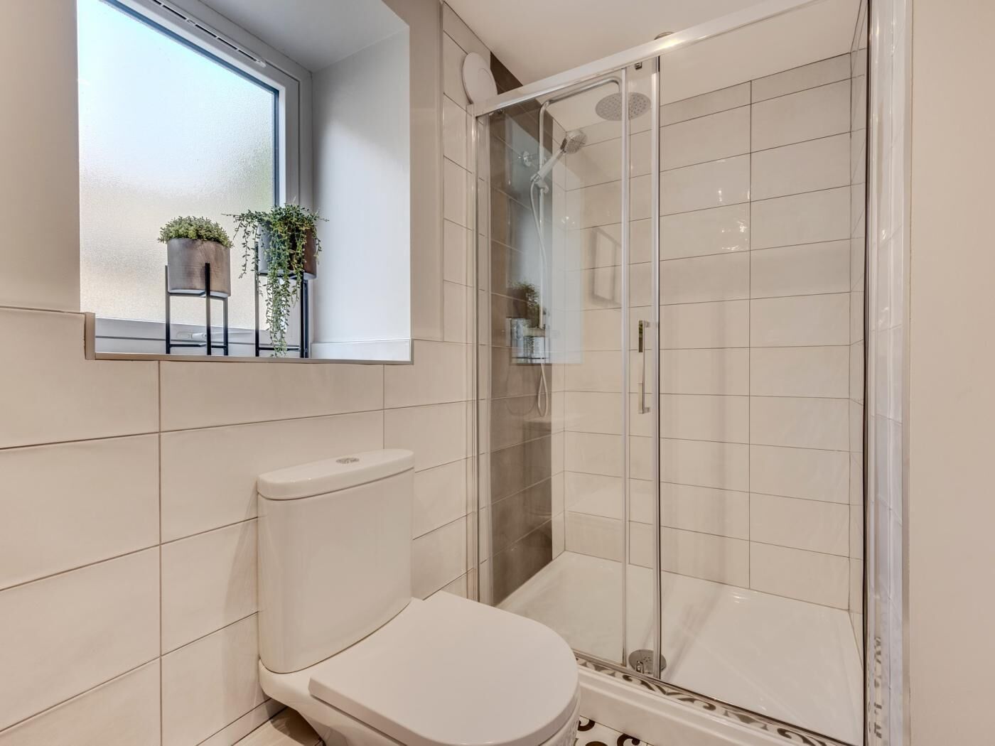 A bathroom with a toilet, a shower enclosure, and a mirror.