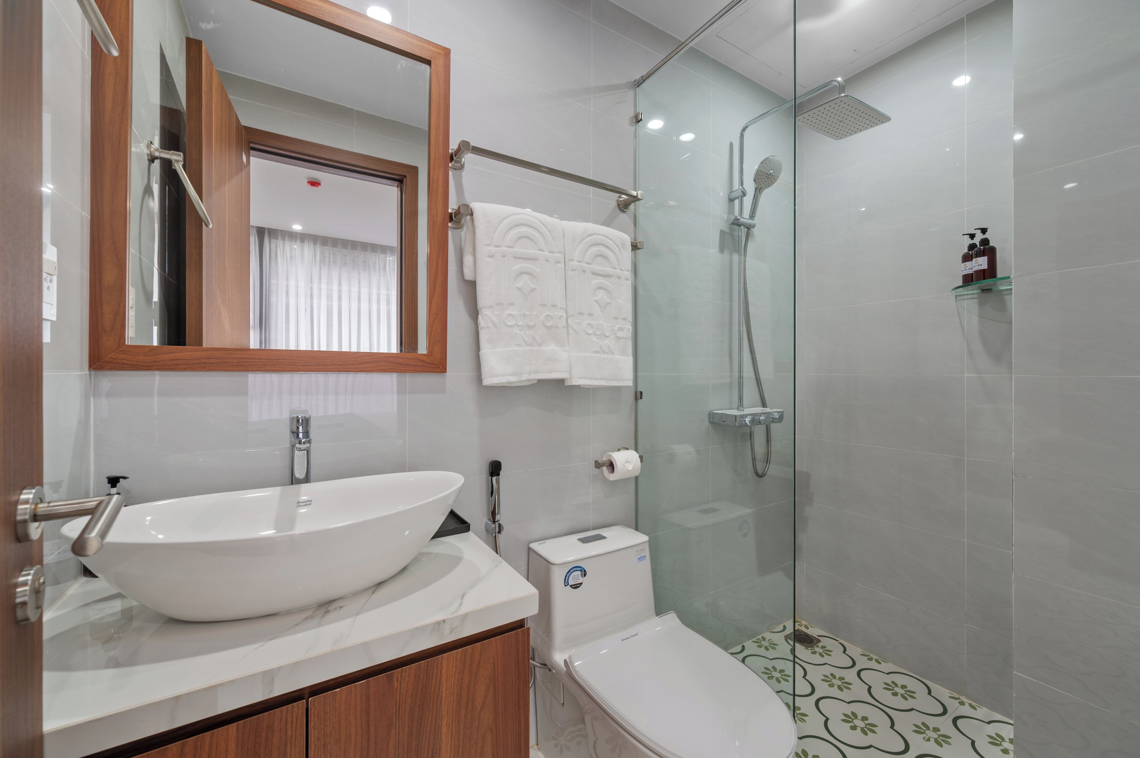 A modern bathroom with a large white vessel sink, a glass-enclosed shower, and a toilet.