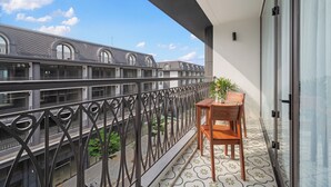 Un balcón con una mesa y sillas, una planta en maceta y vistas a edificios cercanos.