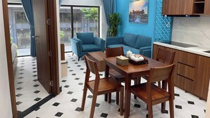 Una sala de estar moderna con comedor, que incluye un conjunto de sofás, una mesa de comedor de madera y una cocina con armarios de madera.