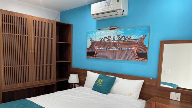 Habitación de hotel con cama, armario de madera, escritorio y aire acondicionado de pared.