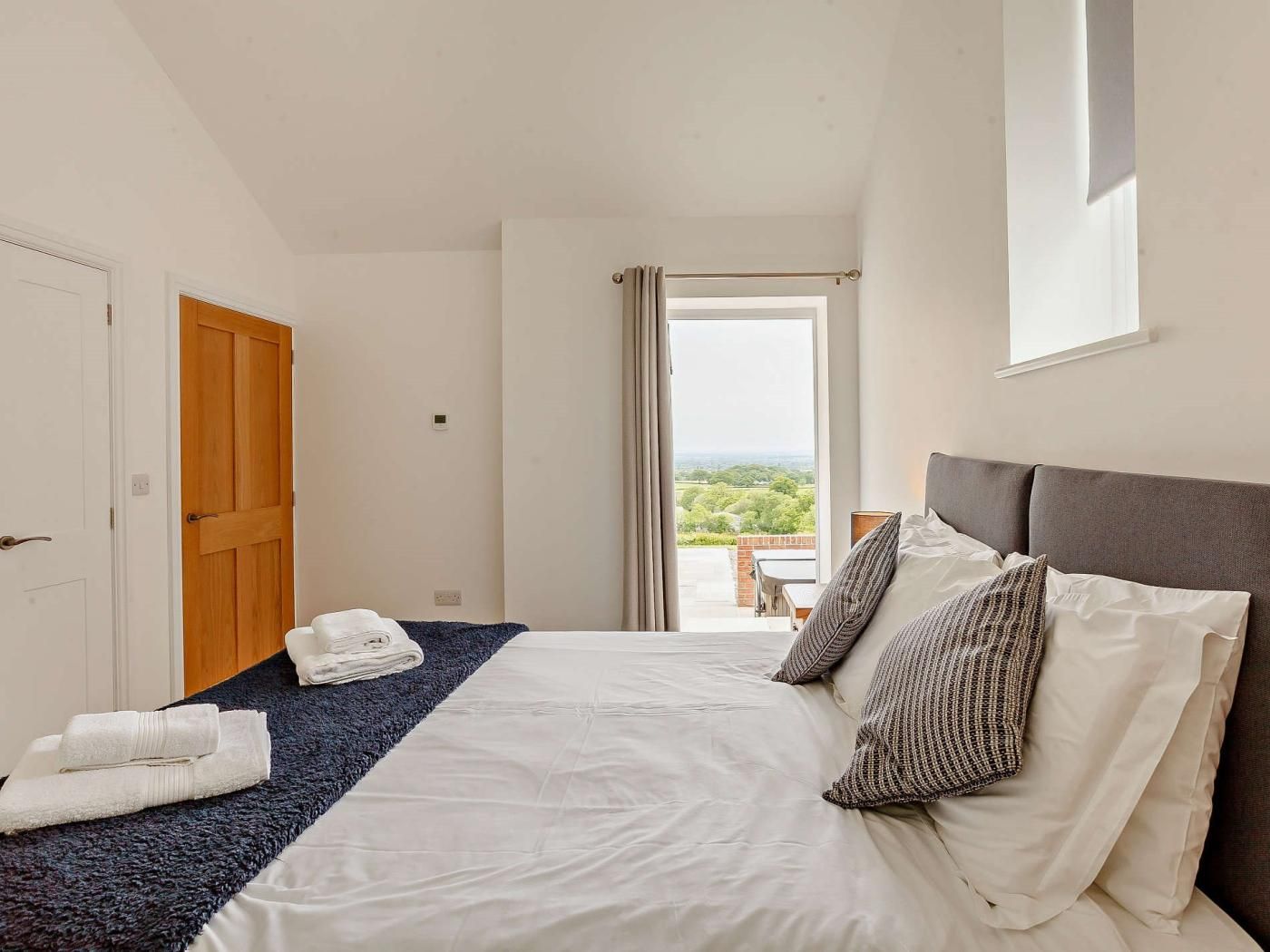 Een hotelkamer met een bed, uitzicht op het landschap en een deur.