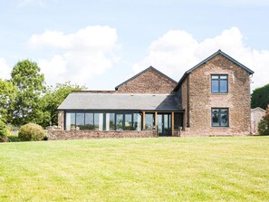 A two-story house with a stone facade, large windows, and a grassy lawn. - 4 Bed in Hereford (oc-83768) (Saint Weonards)