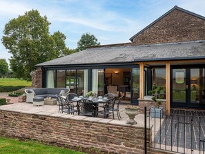 A stone building with a large glass extension, outdoor seating, and a stone wall. - 4 Bed in Hereford (oc-83768) (Saint Weonards)