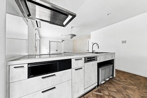 A modern kitchen with a stainless steel range hood, built-in dishwasher, and a large sink. - COSMOS BLANC  (Otaru)