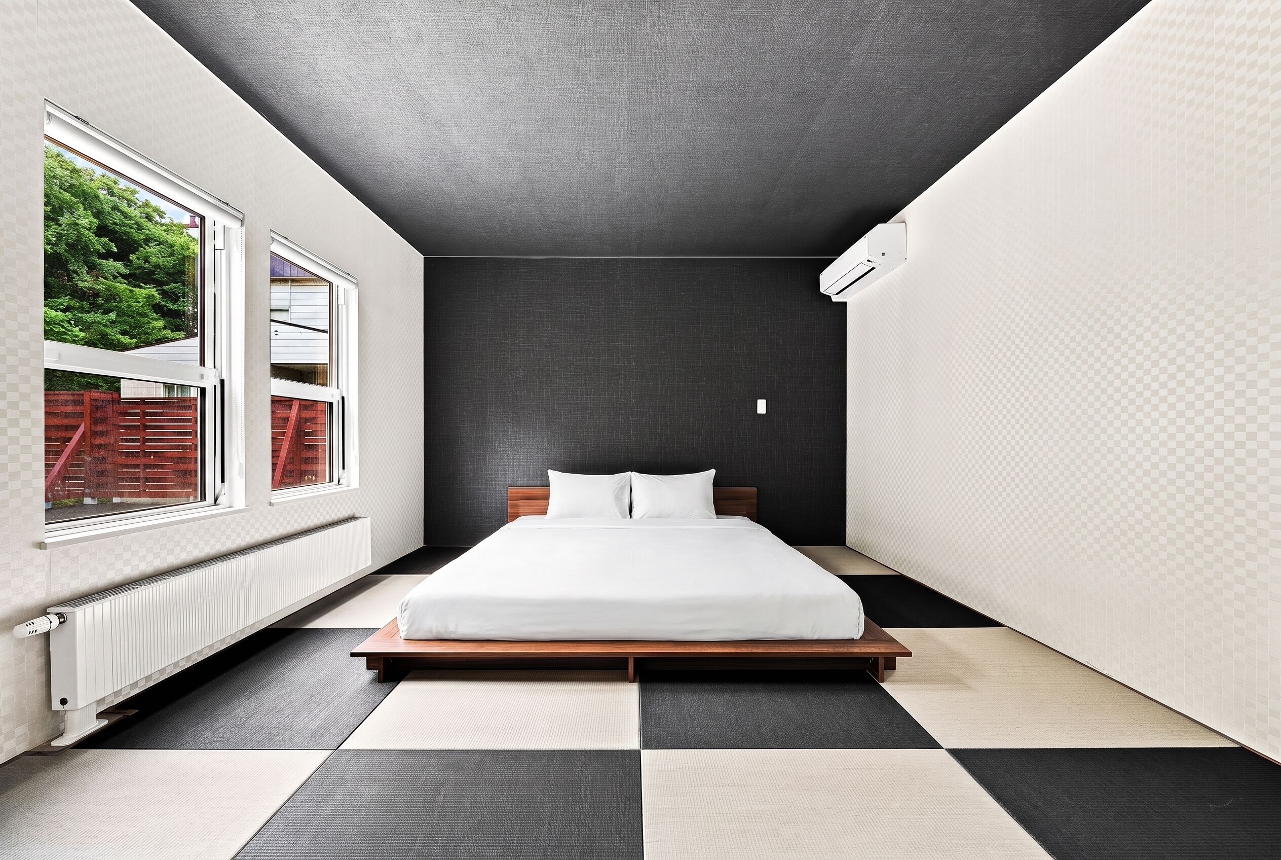 A modern bedroom with a bed, a radiator, and a window with a view of greenery.