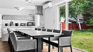A modern kitchen with a large dining table and chairs, a built-in oven, and a view of the outdoors.