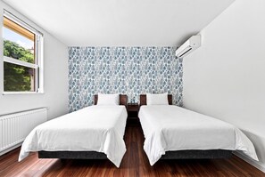 A bedroom with two beds, a radiator, a window with a view, and a patterned wallpaper. - COSMOS BLANC  (Otaru)