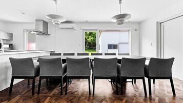 A modern kitchen with a dining area, featuring a large table and chairs, a built-in oven, and a view of the outdoors.